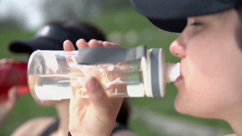 Close Up Two Women Drinking Botttled Water In Slow Motion