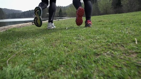 Low Angle Slow Motion Following Two Joggers Running On Grass