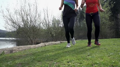 Slow Motion Close Up On Legs Running On Grass Beside Lake