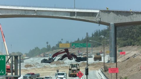 Excavators dig near an empty stretch of the 405 freeway in Los Angles as crews tear down part of a bridge.