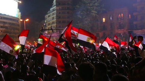 CAIRO, EGYPT, CIRCA 2013 - Protestors wave the Egyptian flag in Cairo, Egypt at a large nighttime rally.