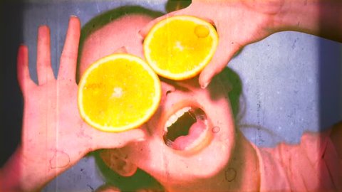 Beauty Model Girl takes Juicy Oranges. Beautiful Joyful teen girl with freckles, funny red hairstyle and yellow makeup. Professional make up. Orange Slices. Old Styled Film in fast motion. Silly Vintage Beauty Theme. 