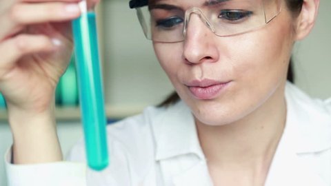 Female scientist mixing and looking at chemicals in test tube

