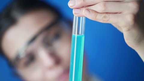 Female chemist looking at test tube with chemicals

