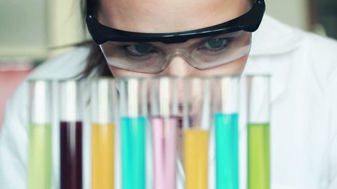Female chemist looking at test tubes with chemicals in laboratory
