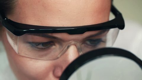 Biochemist examine plant through magnifying glass in laboratory
