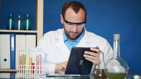 Scientist with tablet computer and test tubes in lab
