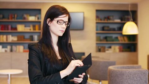 Serious business woman in glasses holds notepad and takes notes in office