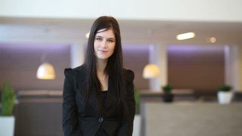 Happy business woman in black suit goes in hall of business center