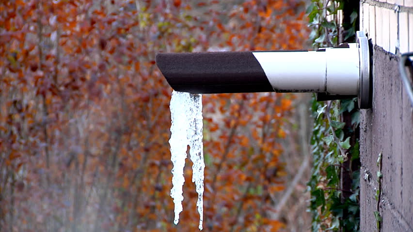 Water vapor emanates and icicles form on an outside exhaust pipe in the winter.