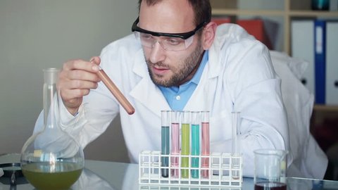 Scientist looking at test tubes with chemicals in laboratory
