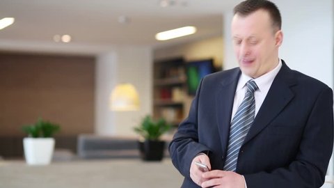 Happy young businessman in suit and tie talks by phone