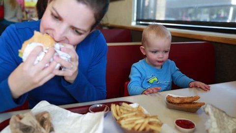 A young family eating food at a fast food restaurant with their toddler