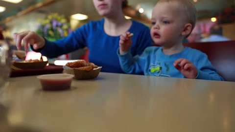 A young family eating food at a fast food restaurant with their toddler