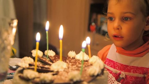 little girl blowing out candles on cake 