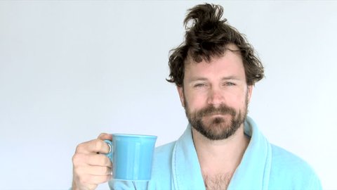 Model released man in studio wearing blue robe drinking coffee in the morning.