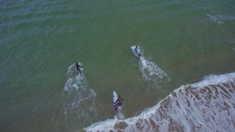 AERIAL: Surfers running into the ocean with surfboards 庫存影片