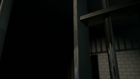 A panning camera closeup of the door slamming shut a brick jail cell with iron bars