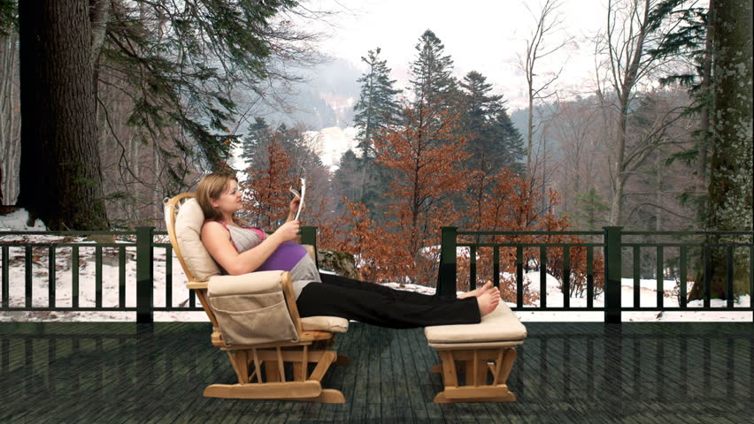 Pregnant woman on rocking chair reading medical papers,mountain resort