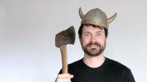 Model released man in studio wearing viking helmet wielding axe.