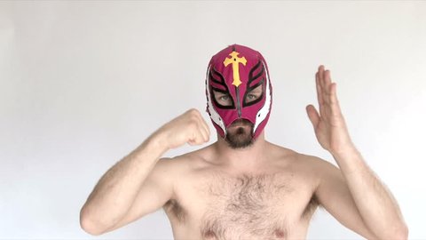 Model released man in studio wearing red lucha libre mask wrestles and challenges viewer.