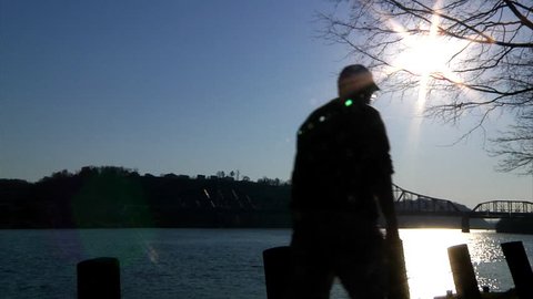 A man walks on the bank of the Ohio River.
