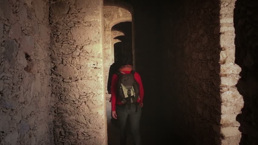 Couple of backpackers walking among the hallways of a labyrinth in search the exit