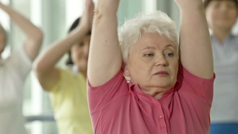 Focus shifting from elderly lady in pink t-shirt to woman in green 