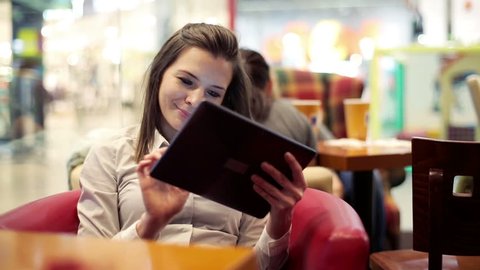 Young attractive woman with tablet computer sitting in cafe
