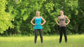 Two young female friends are exercising in the park.