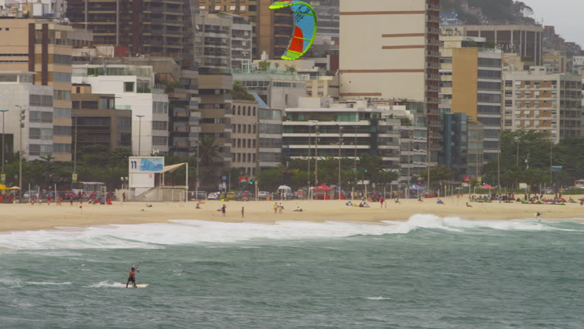 Pan shot of parasailing surfer with Cityscaper in the background.