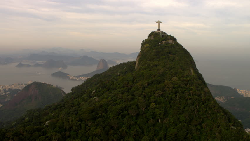 Aerial shot of a religous statue, mountains, buildings, and ocean - Rio de