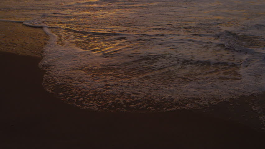 Slow motion, tilt up from ocean ripple to waves on Praia do Diabo (Devil's