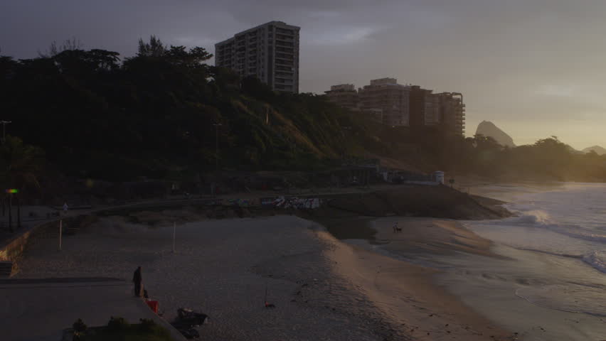 A camera pan of people in the distance on Ipanema Beach at sunset