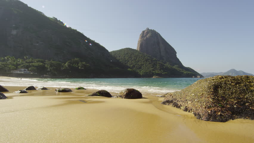 Tracking slow motion shot of Red Beach in Rio with waves washing over exposed