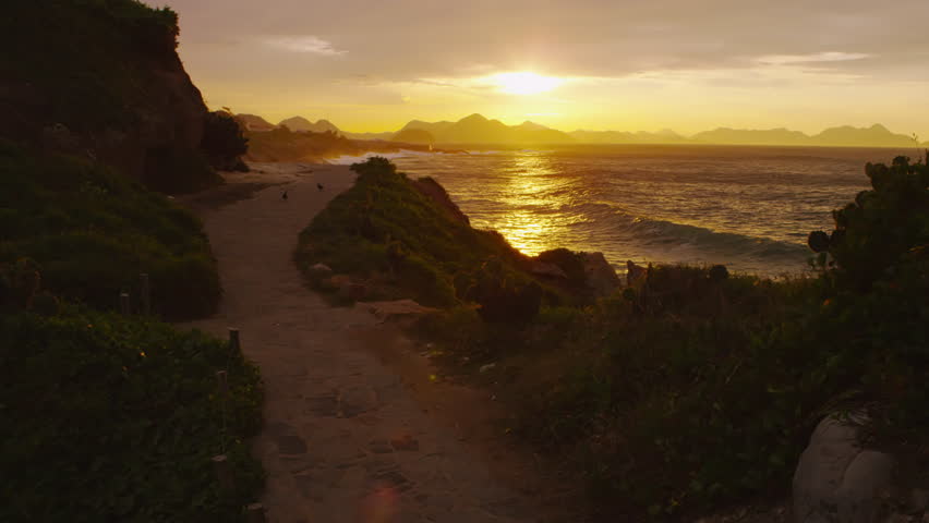 Short pan of sunset over a dirt path overlooking the beach in Rio de Janeiro