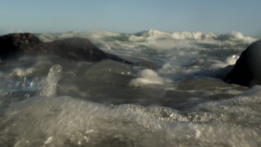 Static and partially submerged shot of waves and rocks.