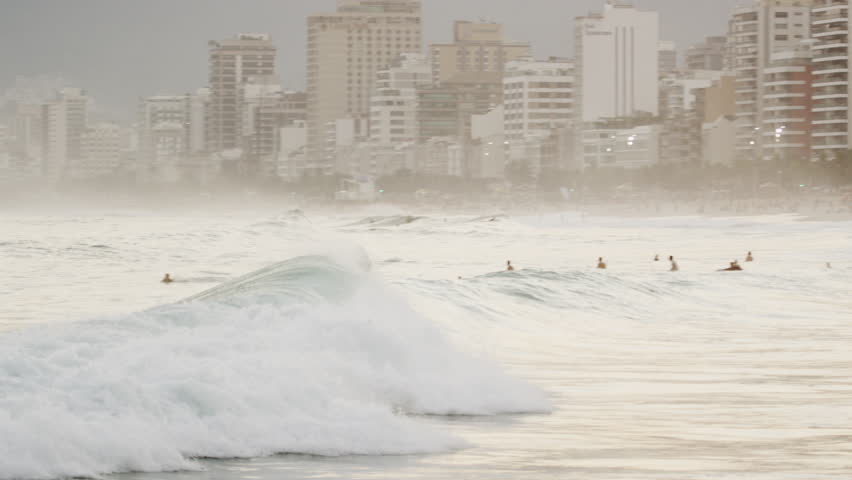 Camera follows surfer riding a wave into Leblon's shoreline