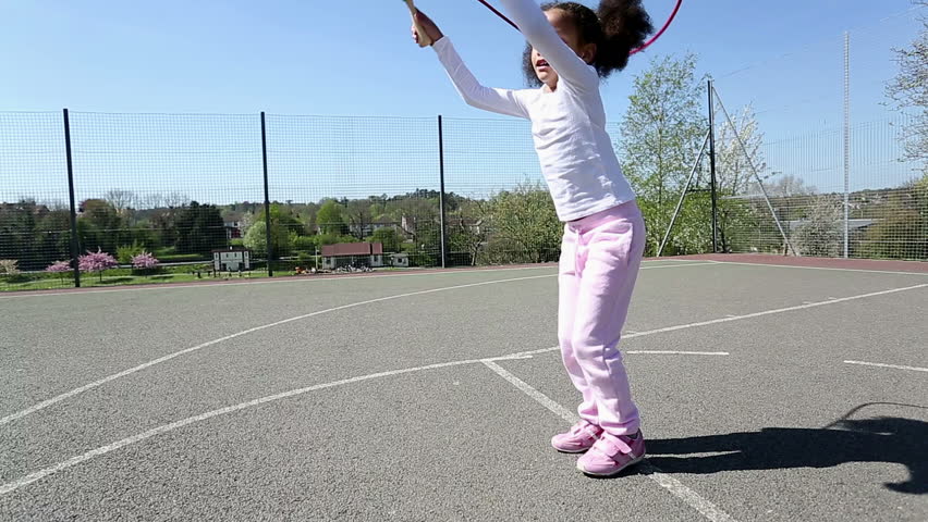 Pretty young five year old girl skipping in a playground on a sunny day