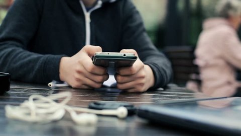 Teenager hands texting on smartphone in cafe
