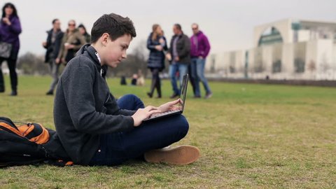 Young teenage student working on laptop in the park
