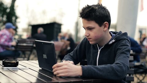 Young teenage student working on laptop in cafe
