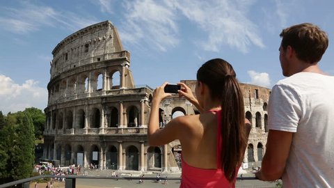 Couple taking picture with smartphone of Colosseum, Rome, Italy. Happy young romantic couple traveling in Europe taking photo with smart phone camera in front of Coliseum. Man and woman.