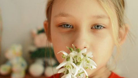 little girl smelling a bouquet of snowdrops, close up