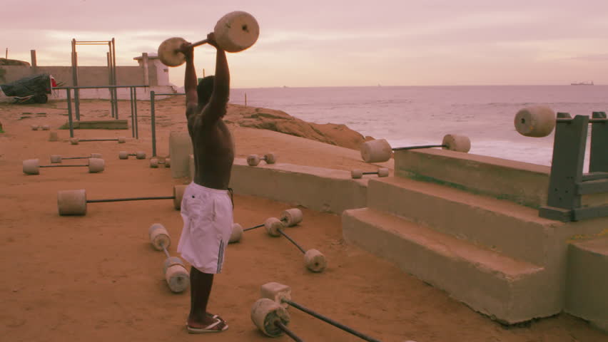 RIO DE JANEIRO, BRAZIL - JUNE: Weightlifting man does one rep at beach in Rio de
