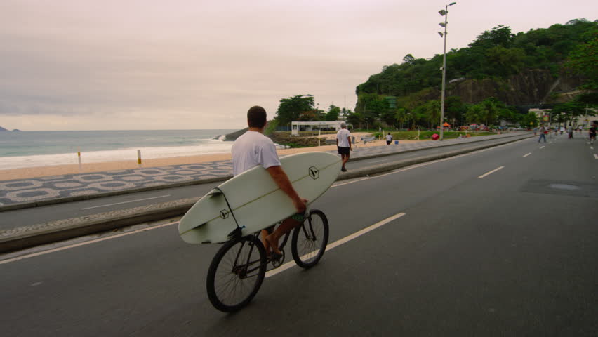 RIO DE JANEIRO, BRAZIL - JUNE 23: Dolly shot, biker + surfboard, Ipanema Beach