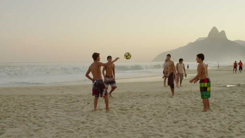 RIO DE JANEIRO, BRAZIL - JUNE 16: Boys kicking a football at the beach on June
