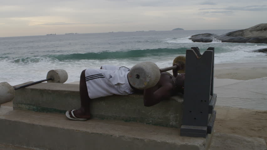RIO DE JANEIRO, BRAZIL - JUNE: Short pan of a man weightlifting at Ipanema beach