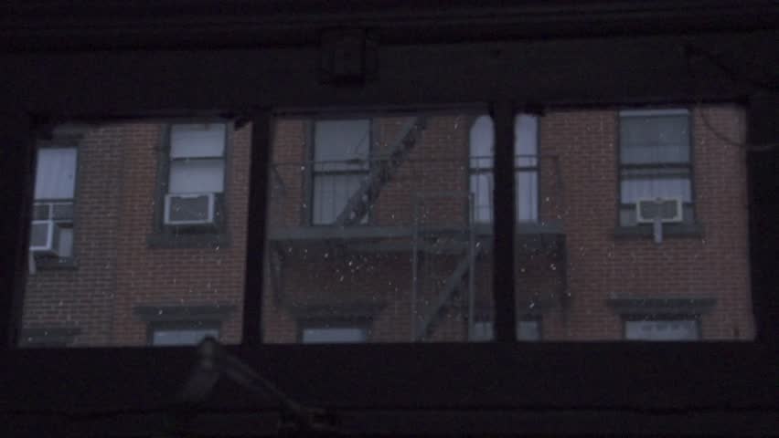 Snow comes down in the city with a brick building in the background. 
