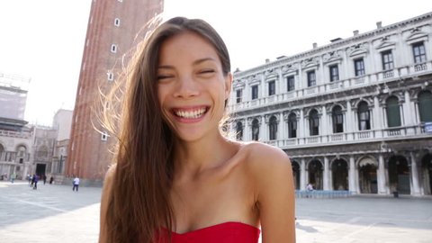 Woman smiling playful on San Marco Square, Italy. Tourist Smiling happy cheerful multiracial girl elegant in summer dress on San Marco Square, Venice, Italy. Caucasian Asian model looking at camera.